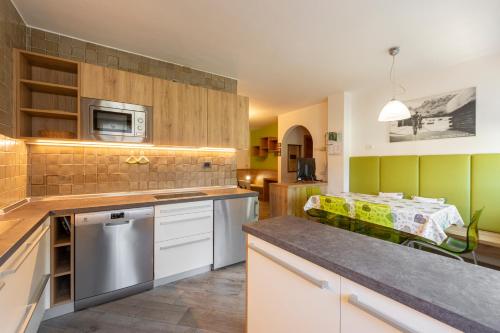 a kitchen with a counter and a table in a room at Tobià de Barat in Pozza di Fassa
