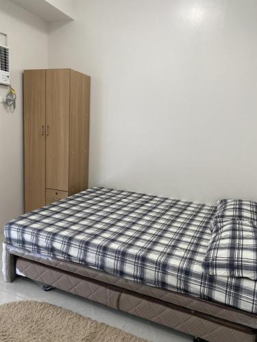a bedroom with a bed and a wooden cabinet at Elegant Studio in Mivela Garden Residences in Banilad