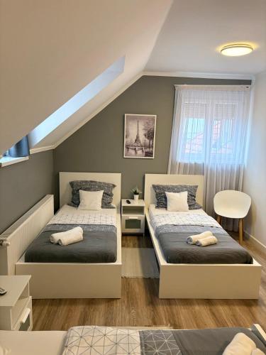 a bedroom with two beds and a window at Budapest Airport Almáskert Panzió in Vecsés