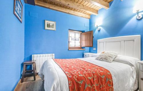 ein Schlafzimmer mit blauen Wänden und einem Bett mit einer roten Decke in der Unterkunft Casa Enacantadora en TresCares Junto a Ruta de el Cares y Picos de Europa in Oceño