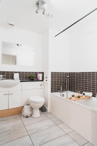 a bathroom with a toilet and a tub and a sink at Modern 2-Bed Near Braehead in Renfrew