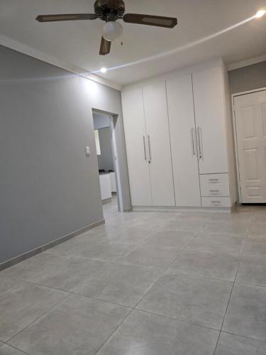 Apartment 33 في خليج ريتشاردز: غرفة فارغة بها دواليب بيضاء ومروحة سقف