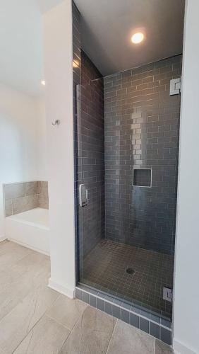 a bathroom with a glass shower with a tub at New Home 3br/25br w/ kayak access sleeps 9 in Orange Beach