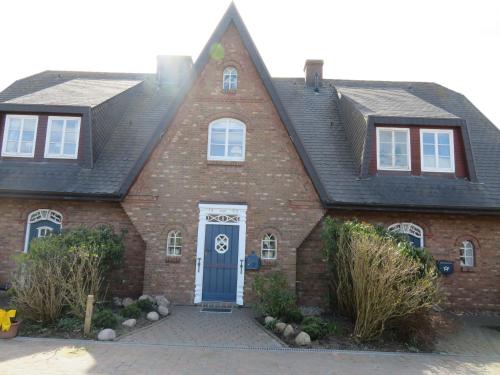 a red brick house with a blue door at Wünderschöner Hausteil Mit Garten in Archsum