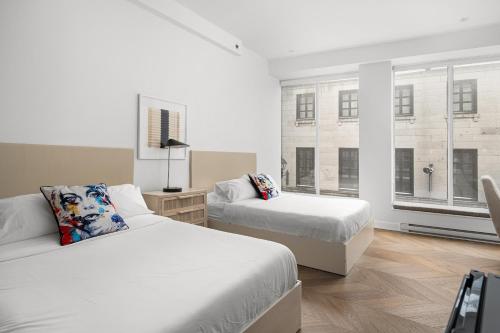 a bedroom with two beds and two windows at The Bowery Loft Suites in Montréal