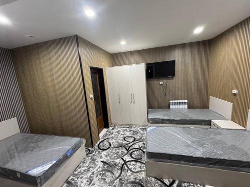 een kamer met twee bedden en een tv aan de muur bij Amiriy hostel in Bukhara