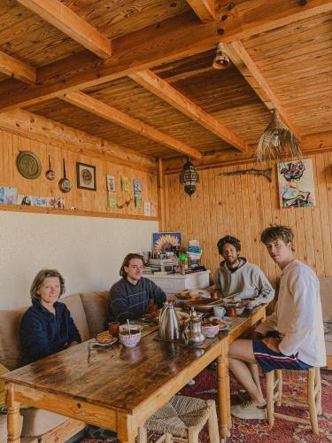 a group of people sitting around a wooden table at Dania Surf House in Mirleft