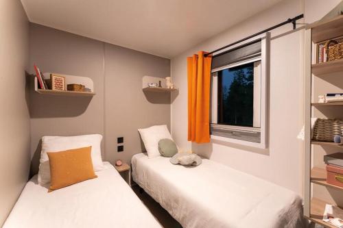 two beds in a small room with a window at Camping les falaises de Toussaint in Toussaint