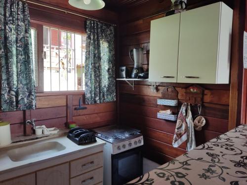 a small kitchen with a sink and a stove at Chalé da Vandisa in Ilhabela