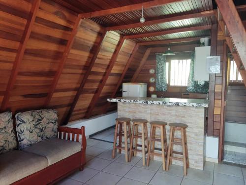 a kitchen with a bar and stools in a room at Chalé da Vandisa in Ilhabela