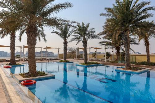 a swimming pool with palm trees in a resort at Beachfront Home with Sea View - 2BR, 134m2 in Lusail