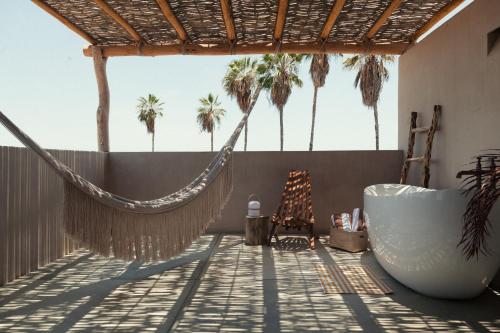 a hammock and a tub on a balcony with palm trees at Proyecto Palmita in El Pescadero