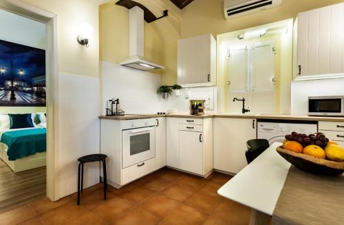 uma cozinha com armários brancos e uma taça de fruta numa mesa em Alfar Aqueduct - Évora House em Évora