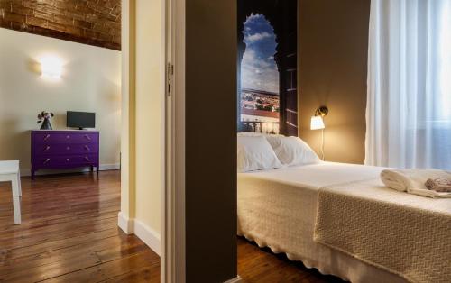 a bedroom with a bed and a dresser with a window at Alfar Aqueduct - Évora House in Évora