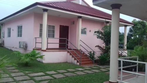 une maison rose avec un escalier devant dans l'établissement Hampton - Resorts, à Hohoe