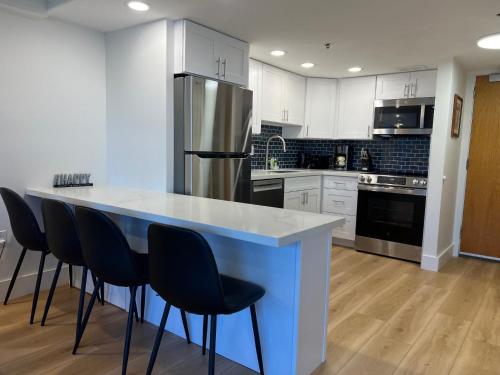 Una cocina con una encimera con sillas y un refrigerador. en Ilikai Tower 1936 condo, en Honolulu
