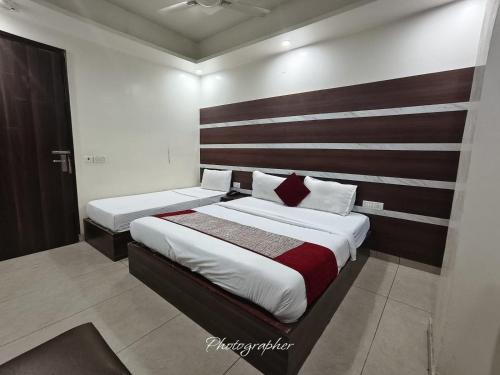 a bedroom with two beds and a wooden headboard at Hotel Blu Bird in New Delhi