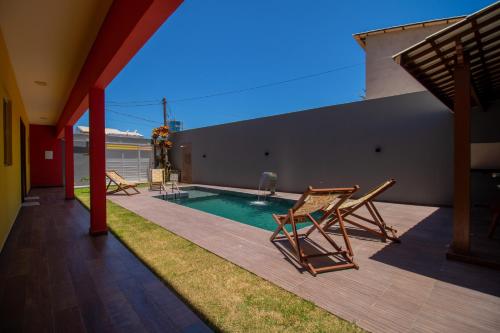 a swimming pool with two deck chairs next to a house at Zen Spa Houses in São Miguel dos Milagres