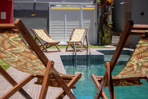 four chairs sitting in the water next to a pool at Zen Spa Houses in São Miguel dos Milagres