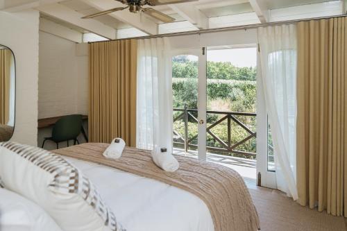 a bedroom with a large bed and a large window at Klein Champagne Guesthouse and Cottages in Franschhoek