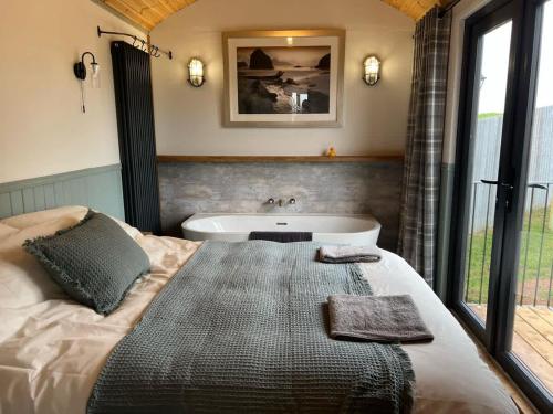 ein Schlafzimmer mit großem Bett und Badewanne in der Unterkunft Bramley Shepherds Hut - Whimple in Whimple