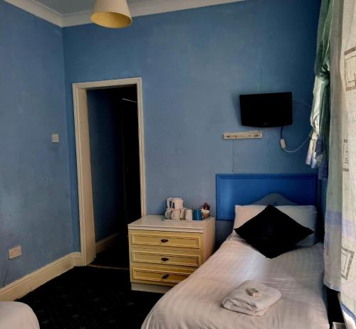 a blue bedroom with a bed and a dresser at The New Osterley Hotel in Blackpool