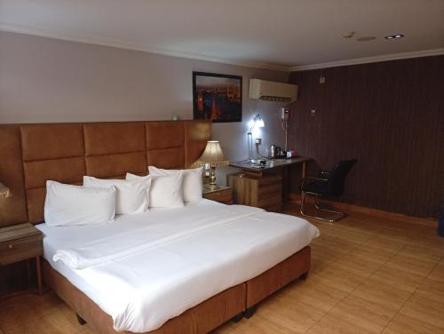 a hotel room with a large bed and a desk at Li Tour International Hotel in Ikeja