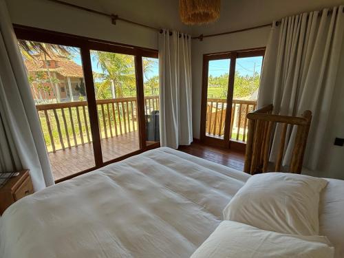 una camera con letto e un balcone con porte scorrevoli in vetro di Corumbau Bangalôs a Corumbau