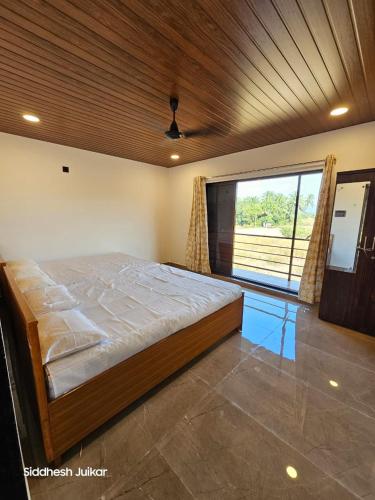 ein Schlafzimmer mit einem großen Bett und einem großen Fenster in der Unterkunft Anugraha Homestay in Alībāg