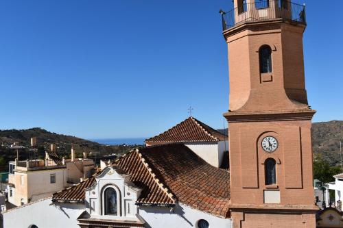 a building with a clock tower in a town at Zentral Gelegene Wohnung in Cómpeta