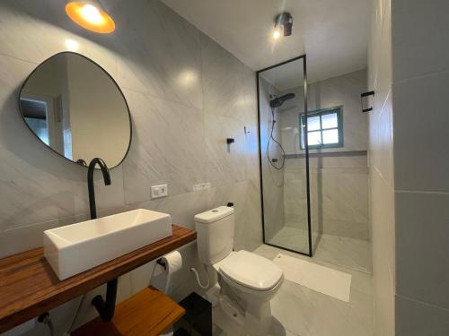 a bathroom with a toilet and a sink and a mirror at Caiçara Guest House in Ubatuba