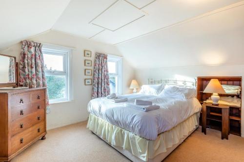 ein Schlafzimmer mit einem Bett, einer Kommode und zwei Fenstern in der Unterkunft Cornerways in Worth Matravers