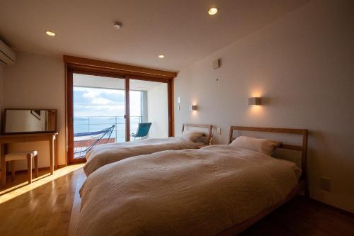 two beds in a room with a large window at USHIMADO Villa - Vacation STAY 61741v in Setouchi