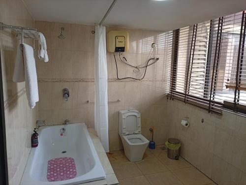 a bathroom with a bath tub and a toilet at Li Tour International Hotel in Ikeja