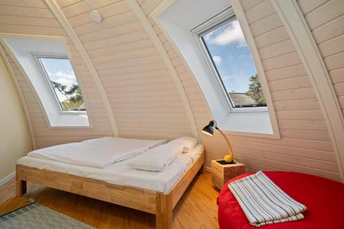 ein Schlafzimmer mit einem Bett und zwei Fenstern in der Unterkunft Nordkugel - Rundes Wohnglück am Tollensesee in Wustrow