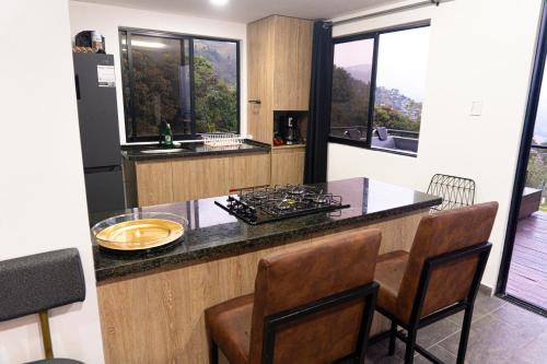 eine Küche mit einer Theke und einigen Stühlen und Fenstern in der Unterkunft Finca Moderna 2 Habitaciones con Jacuzzi Privado, Vistas Panorámica 