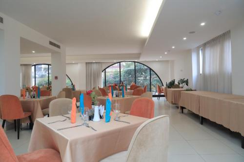 a dining room with tables and chairs and a room with windows at Hotel Boutique Elmos - Meskel Flower in Addis Ababa