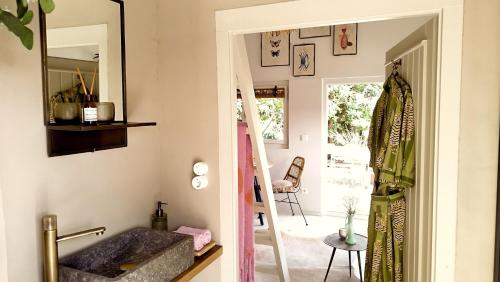 ein Bad mit einem Spiegel und einem Waschbecken im Zimmer in der Unterkunft CoCo Cabin Luxe Tiny House - Privé Hottub - Strand & zwemvijver - Privacy in Woudenberg