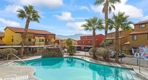 a swimming pool with palm trees and buildings at Newly Renovated Condo in Mesquite