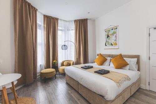 a bedroom with a large bed and a table and chair at Amazing serviced accommodations for Corporate Contractors and Leisure clients Located at a walking distance from three majors Underground and Overground stations in London