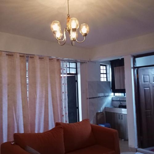 un soggiorno con un divano e un lampadario di Pamsal Studio a Thika