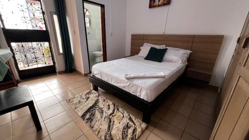 a bedroom with a bed and a bathroom with a window at BARAN Home in Yaoundé
