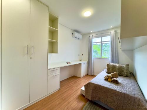 ein Schlafzimmer mit Bett, Schreibtisch und Fenster in der Unterkunft Apto a 10 min da Vila Germânica, dois quartos, salas de estar e jantar, cozinha completa, sacada com churrasqueira, Wi-Fi, Piscina, academia, mercadinho 24 horas e Vaga de garagem in Blumenau