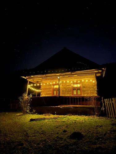 a wooden house with lights on it at night at Glamping - Casuta de pe Fiad in Romuli