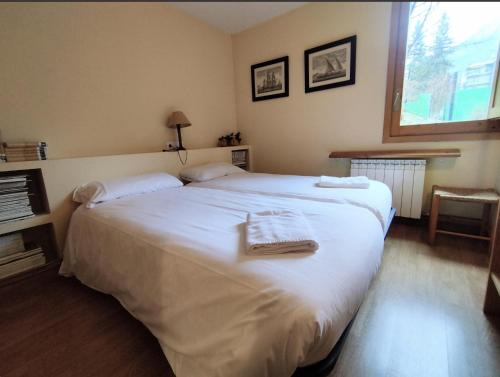 a bedroom with a large white bed with towels on it at Check-in Casas Alvaro in Cerler