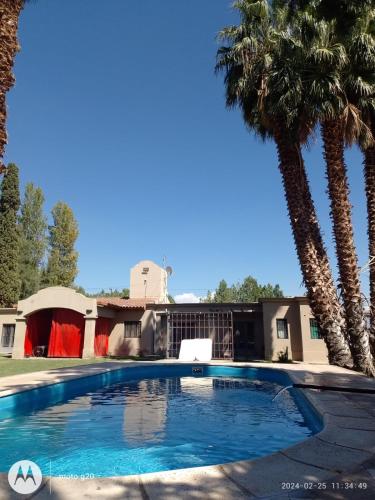 a swimming pool in front of a house with palm trees at La gran morada in Corralitos