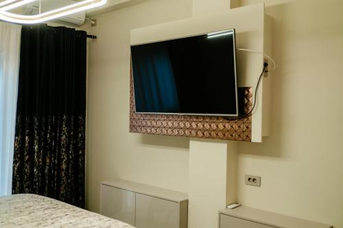 a flat screen tv on the wall of a bedroom at Jessica luxury Apartament in Curtea de Argeş