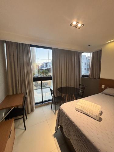 a hotel room with a bed and a table and a window at Azzure Apartmento 103 Intermares in Cabedelo