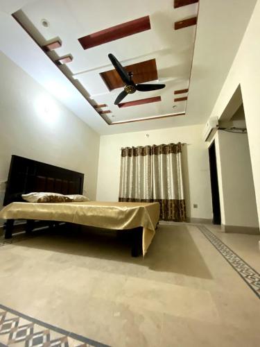 ein Schlafzimmer mit Bett und Deckenventilator in der Unterkunft Suites Inn in Faisalabad