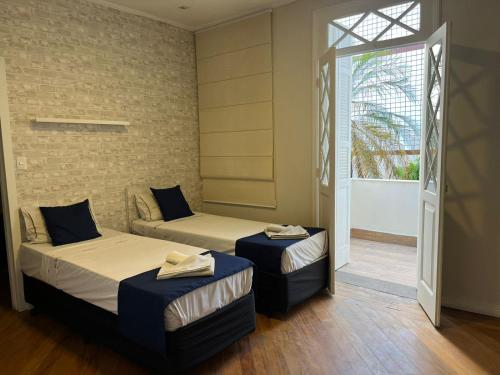 a room with two beds and a window and a door at Palais House in São Vicente